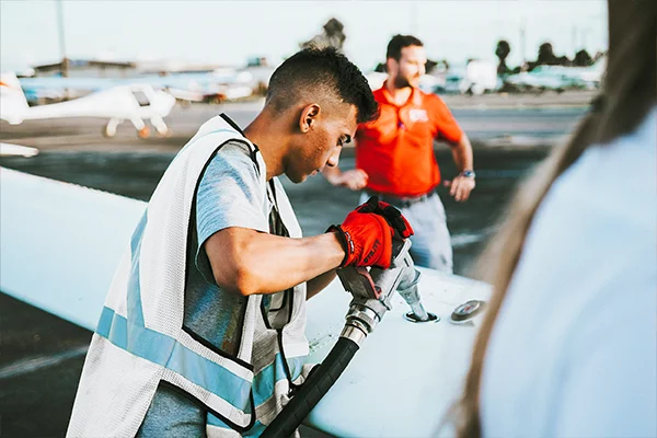 Male Oleum Fuels staff member refuelling a jet via the wing's fuel gauge